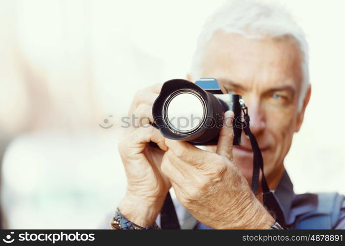 Senior man with camera in city. Looking for good shoots