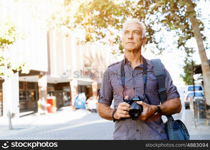 Senior man with camera in city. Looking for good shoots