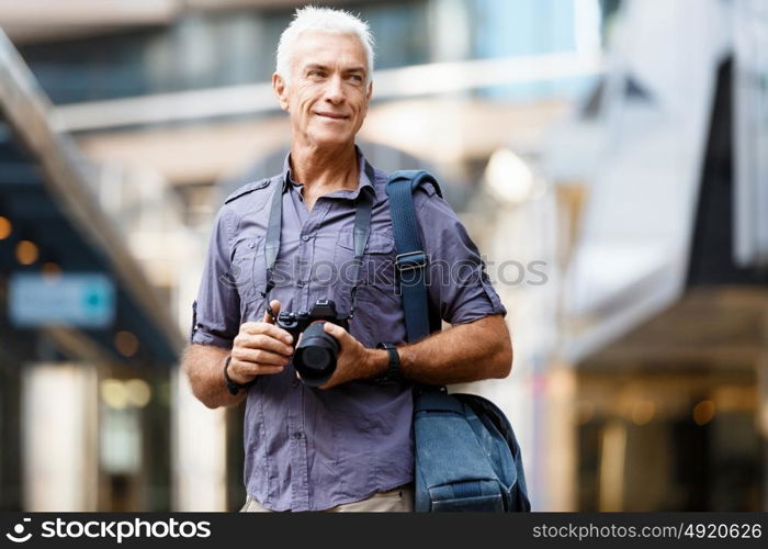 Senior man with camera in city. Looking for good shoots