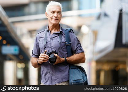 Senior man with camera in city. Looking for good shoots