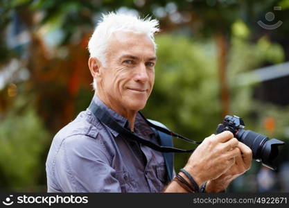 Senior man with camera in city. Looking for good shoots