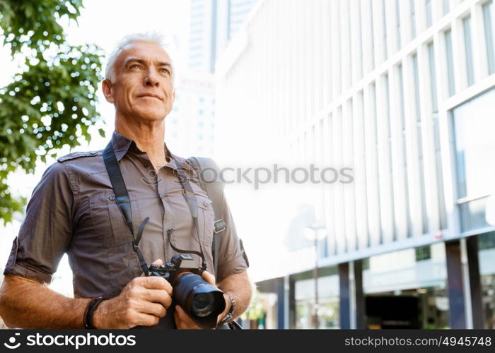 Senior man with camera in city. Looking for good shoots