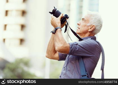 Senior man with camera in city. Looking for good shoots