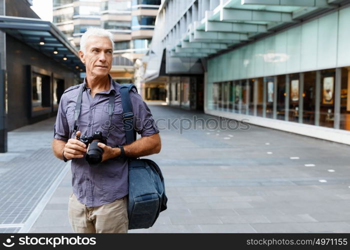 Senior man with camera in city. Looking for good shoots