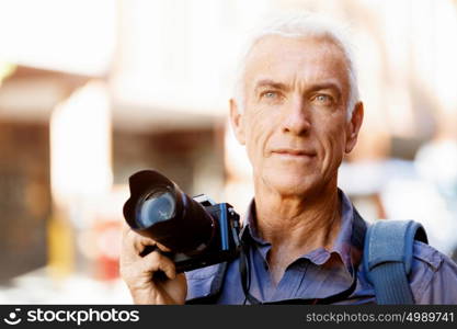 Senior man with camera in city. Looking for good shoots