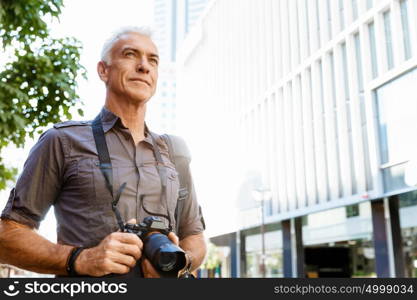 Senior man with camera in city. Looking for good shoots