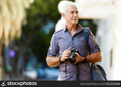 Senior man with camera in city. Looking for good shoots