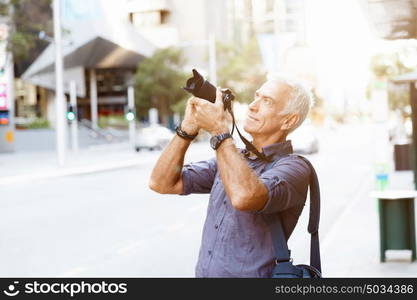 Senior man with camera in city. Looking for good shoots