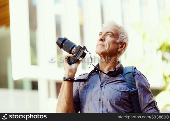 Senior man with camera in city. Looking for good shoots