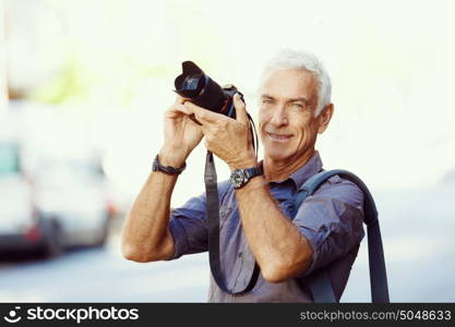 Senior man with camera in city. Looking for good shoots