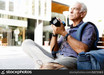 Senior man with camera in city. Looking for good shoots