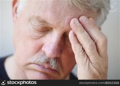 Senior man with fingers over painful headache, eyes closed