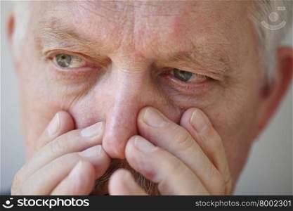 Senior man with fingers pressing on nose