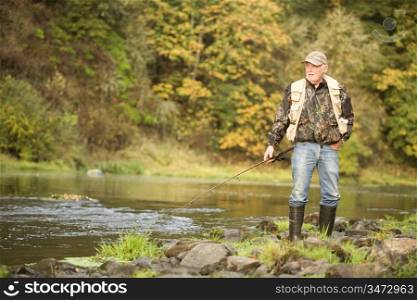 Senior Man with Fishing Rod on Bank of River