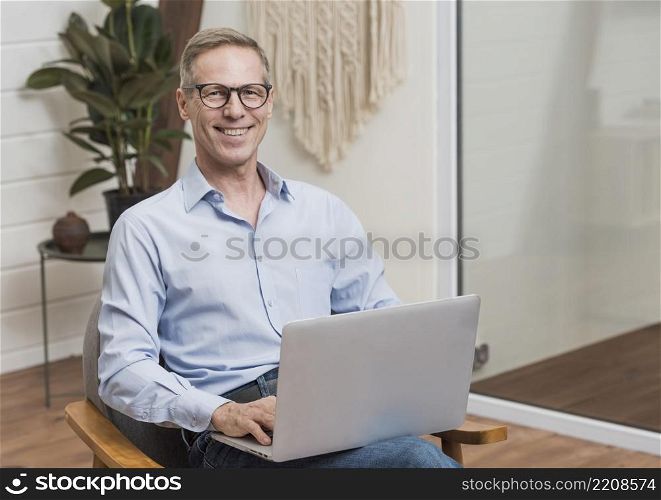 senior man with glasses holding laptop
