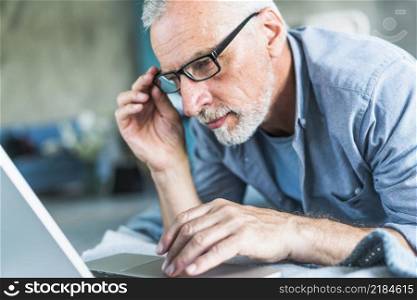 senior man with hand eyeglasses looking laptop