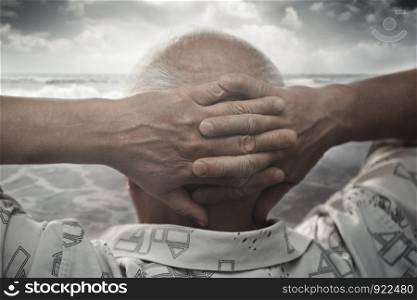 Senior man with hands behind his head looking at the sea