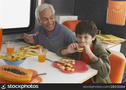 Senior man with his grandson having meal at the dining table