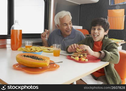 Senior man with his grandson having meal at the dining table