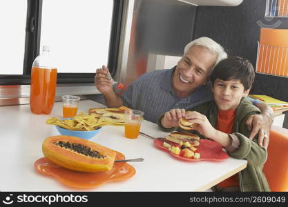 Senior man with his grandson having meal at the dining table