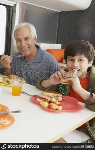 Senior man with his grandson having meal at the dining table