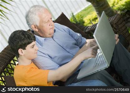 Senior man with his grandson using a laptop