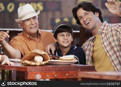 Senior man with his son and grandson sitting in a restaurant and smiling