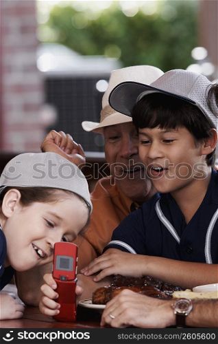 Senior man with his two grandchildren looking at a mobile phone