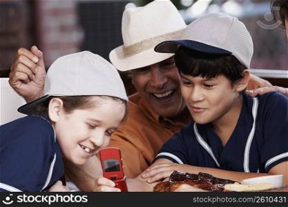 Senior man with his two grandchildren looking at a mobile phone and smiling
