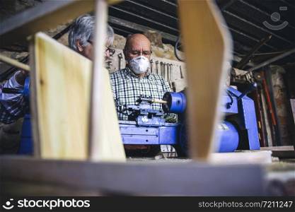 Senior man with protective mask working in a carpentry workshop