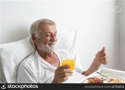 senior man with smiling and thump up cheer on bed at nursing home