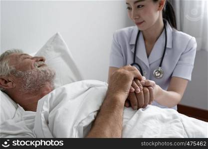 senior man with smiling nurse, takes care and cheer on bed at nursing home