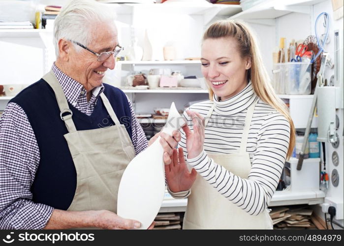 Senior Man With Teacher Looking At Vase In Pottery Class