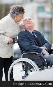 senior man with woman in wheelchair outside in the city