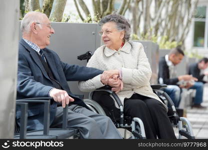 senior man with woman in wheelchair sat outside