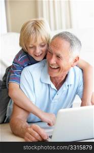 Senior man with young boy using laptop computer