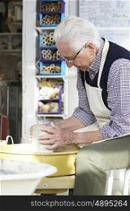 Senior Man Working At Pottery Wheel In Studio