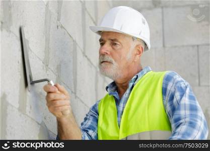 senior man working on wall construction