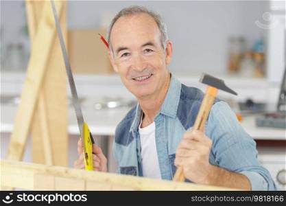 senior man working with wood and holding tools