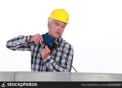 Senior mason drilling into wall