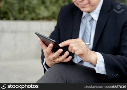 Senior (mature) businessman using digital tablet at a outdoor