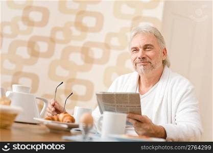 Senior mature man - breakfast at home with newspaper at desk