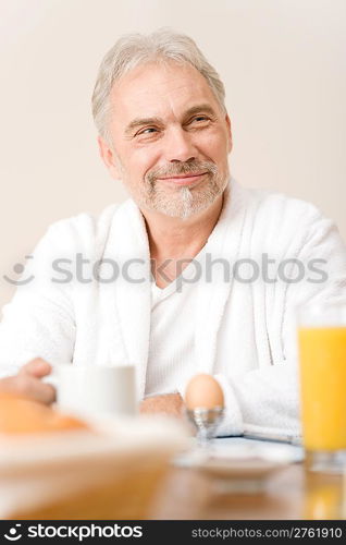 Senior mature man - breakfast at home with orange juice, coffee and egg