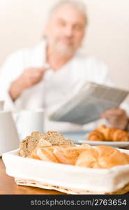 Senior mature man - breakfast pastry and bread in wicker basket