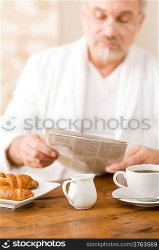 Senior mature man having breakfast, coffee, croissant