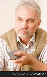 Senior mature man holding remote control in hand