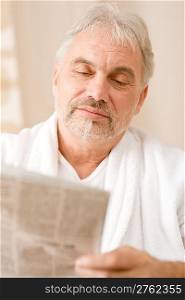 Senior mature man thoughtful read newspaper wear bathrobe