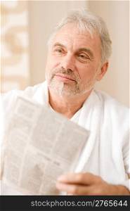 Senior mature man thoughtful read newspaper wear bathrobe