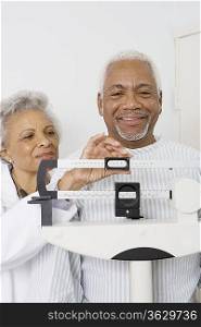Senior medical practitioner checks weight of patient