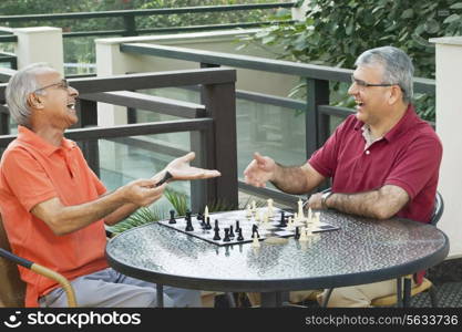 Senior men laughing while playing chess